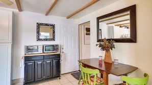 A compact kitchen with a microwave, toaster, and cabinet. There is a dining table with chairs and a mirror above it. - Green Valley Vacation Rental Apt w/ Patio & Grill! (Green Valley)