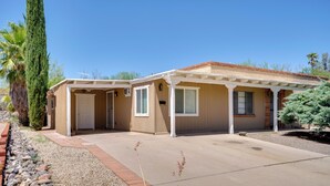 A two-story house with a covered patio, a front door, and a small garden area with rocks and a palm tree. - Green Valley Vacation Rental Apt w/ Patio & Grill! (Green Valley)