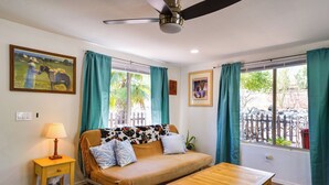 A room with a sofa, a wooden table, a lamp, and curtains. - Green Valley Vacation Rental Apt w/ Patio & Grill! (Green Valley)