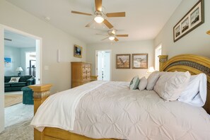 A bedroom with a large bed, a ceiling fan, and a wooden headboard.