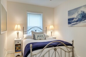 A bedroom with a bed, two bedside lamps, a window, a bookshelf, and a painting on the wall.