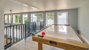 Une pièce spacieuse avec une table de billard, de grandes fenêtres et une vue sur l’eau.
