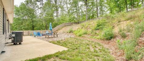 A backyard with a concrete patio, a wooden fence, and a picnic table.