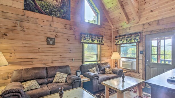 Ein gemütliches Blockhaus-Interieur mit Holzwänden, zwei Sofas, einem Couchtisch und einer Tür mit Fenster.