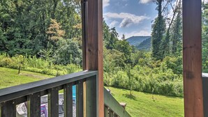 Eine Holzterrasse mit Blick auf eine üppige, grüne Landschaft und ein fernes Bergmassiv.