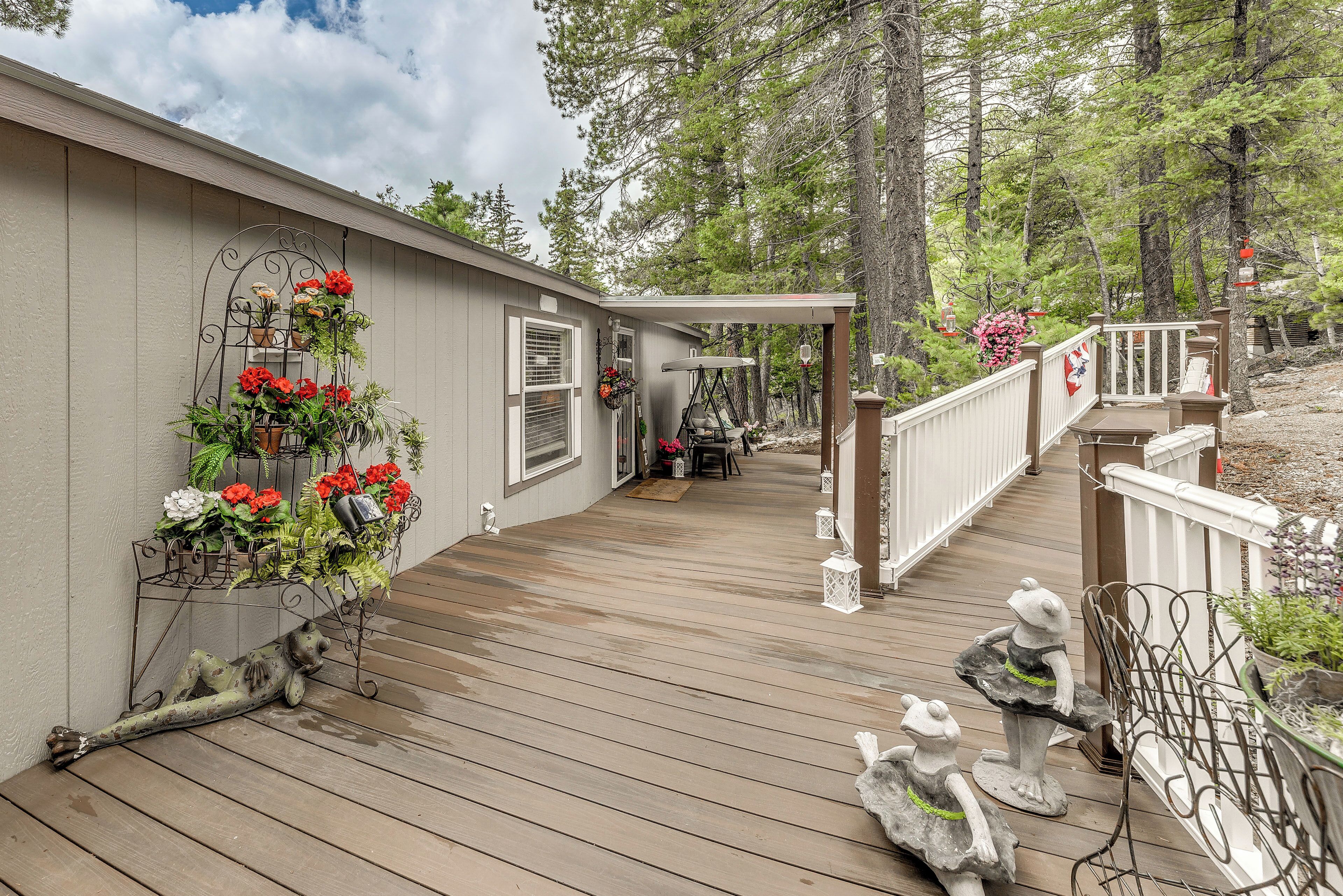 A wooden deck with a railing, potted plants, and outdoor furniture.