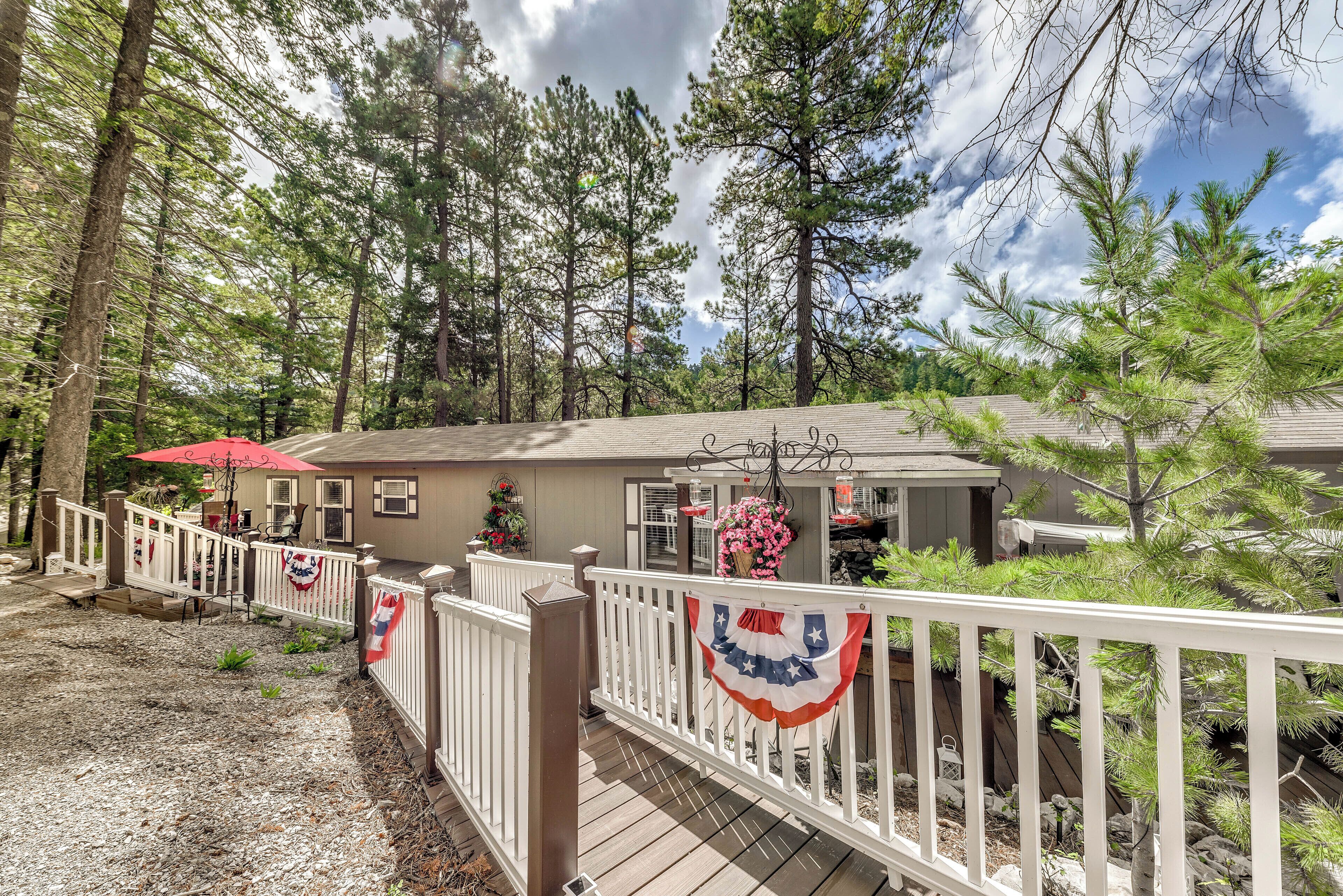 A wooden deck with white railings, a red umbrella, and a house with a small porch area.