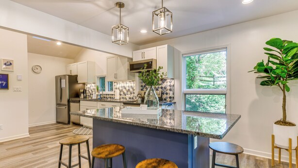 A modern kitchen with a central island, bar stools, and pendant lighting. - Waynesville Cabin w/ Pickleball Court and Hot Tub (Waynesville)