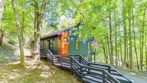 A cabin with a wooden staircase leading up to a porch, surrounded by trees. - Waynesville Cabin w/ Pickleball Court and Hot Tub (Waynesville)