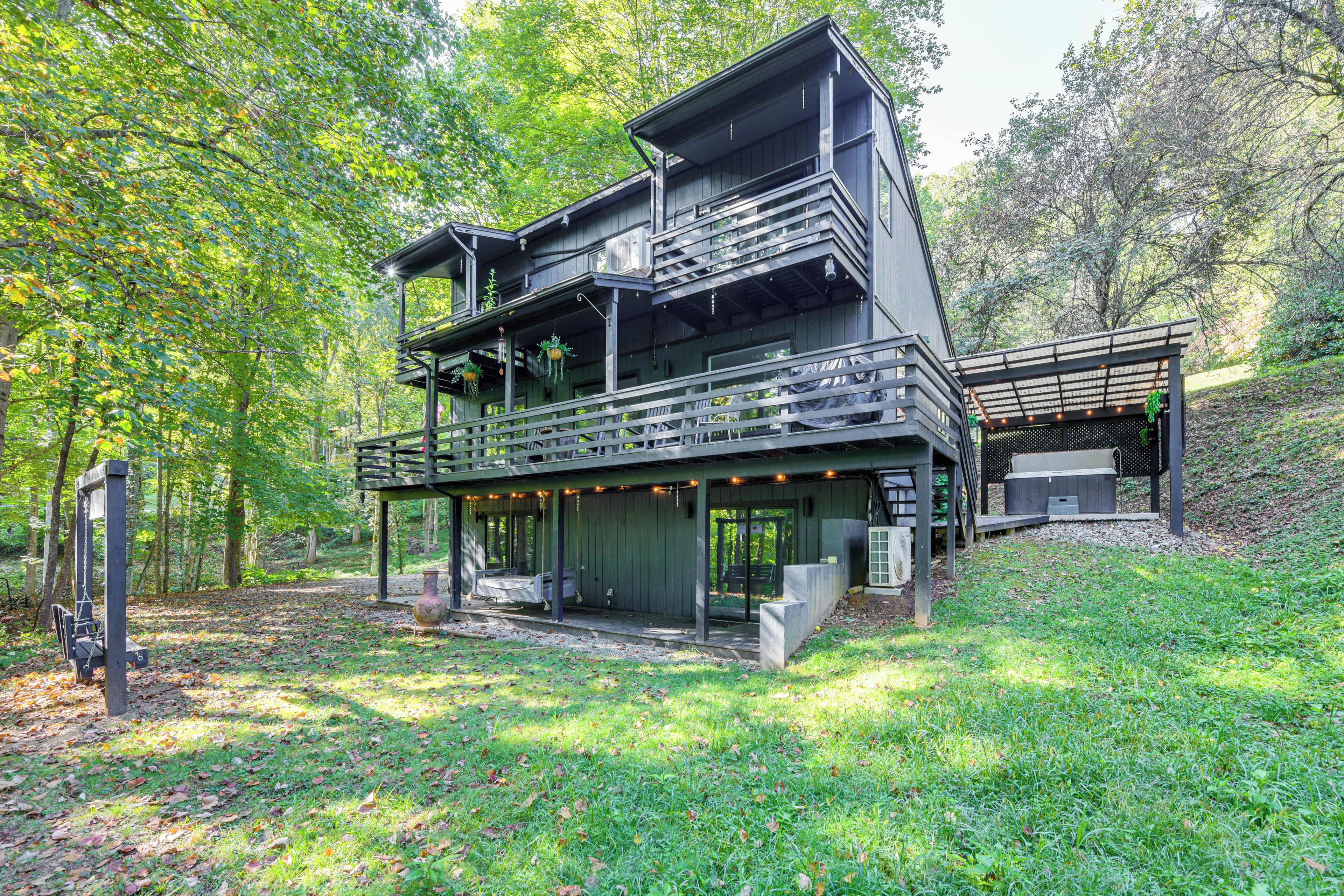 A multi-level wooden cabin with a balcony, surrounded by trees.