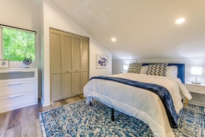 A bedroom with a bed, a dresser, a closet, and a window with a view of trees. - Waynesville Cabin w/ Pickleball Court and Hot Tub (Waynesville)