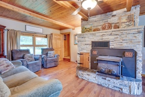 A cozy living room with a stone fireplace, wooden ceiling beams, and comfortable seating.