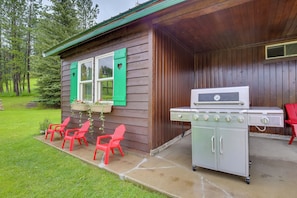 Eine Holzhütte mit Grill und Sitzgelegenheit im Freien.