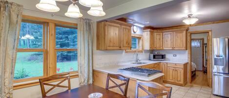 A kitchen with wooden cabinets, a dining table, and a chandelier.