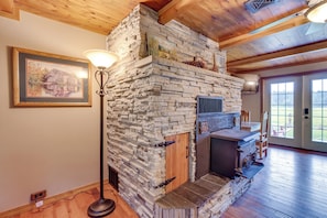 A stone fireplace with a wooden door, a floor lamp, and a framed picture on the wall.