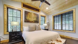 A bedroom with a large bed, wooden ceiling, and large windows. - Grill + Water Views: Chinquapin Resort Home (Glenville)