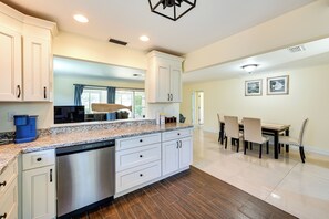 A modern kitchen with white cabinetry, granite countertops, and stainless steel appliances. There is a dining area with a table and chairs. - Pet-friendly Naples Vacation Rental Near Beach! (Naples)