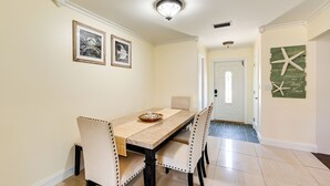 Een eethoek met een tafel en stoelen, kunstwerken aan de muur en een welkomstbord.