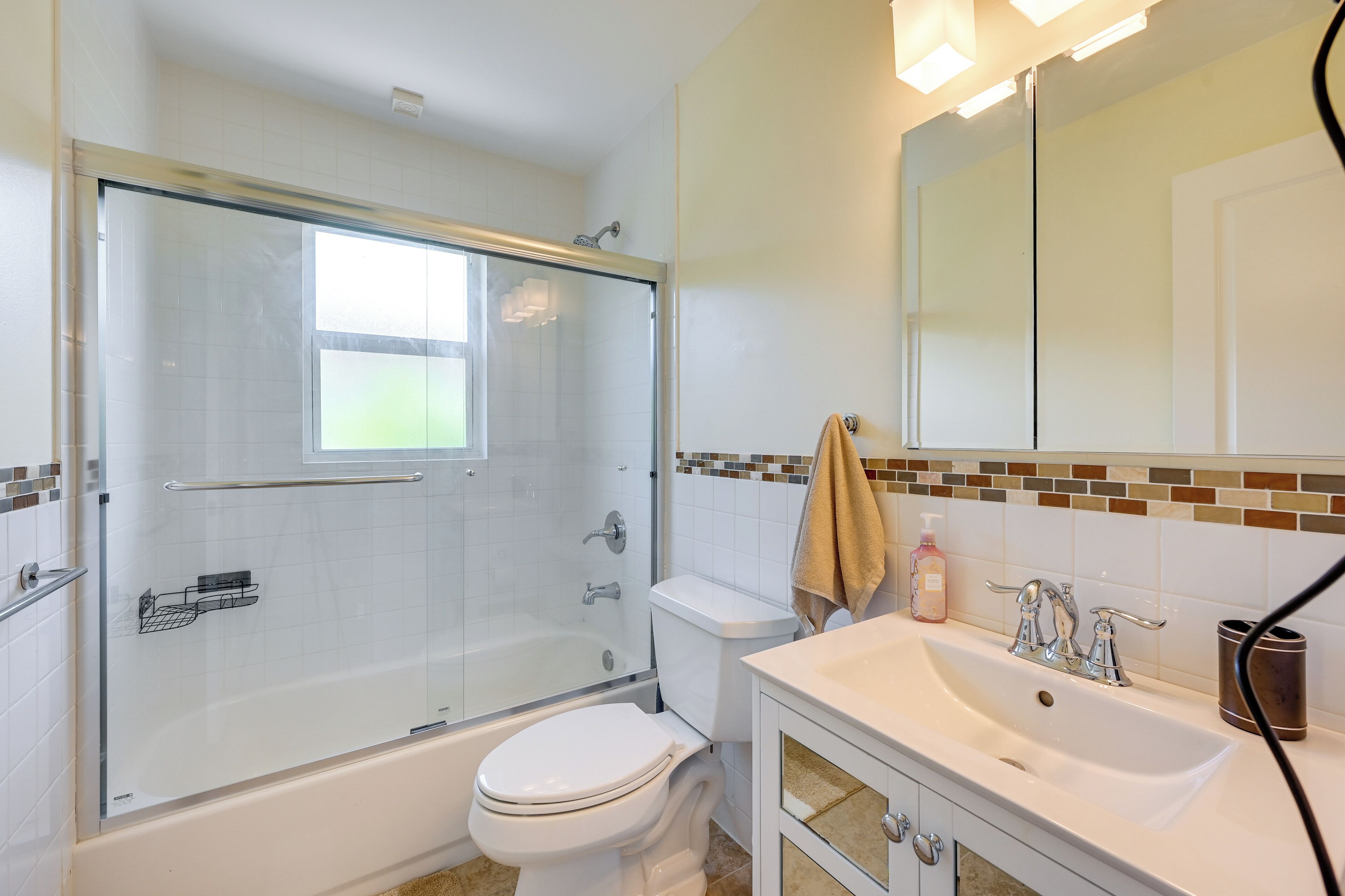 Une salle de bain moderne avec une douche à parois de verre, des toilettes blanches et un meuble-lavabo avec un évier et un miroir.