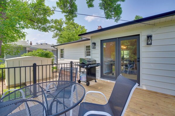 A patio with a metal table and chairs, a grill, and a sliding glass door leading to a covered area. - Renovated Rapid City Home Near Sturgis Rally Week! (Rapid City)