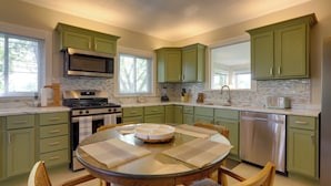 A kitchen with green cabinets, a stainless steel refrigerator, a dishwasher, a microwave, and a stove. - Welcoming Port Clinton Vacation Rental! (Port Clinton)