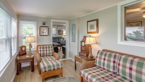 A cozy living room with wicker furniture, a fireplace, and a view into the dining area. - Welcoming Port Clinton Vacation Rental! (Port Clinton)