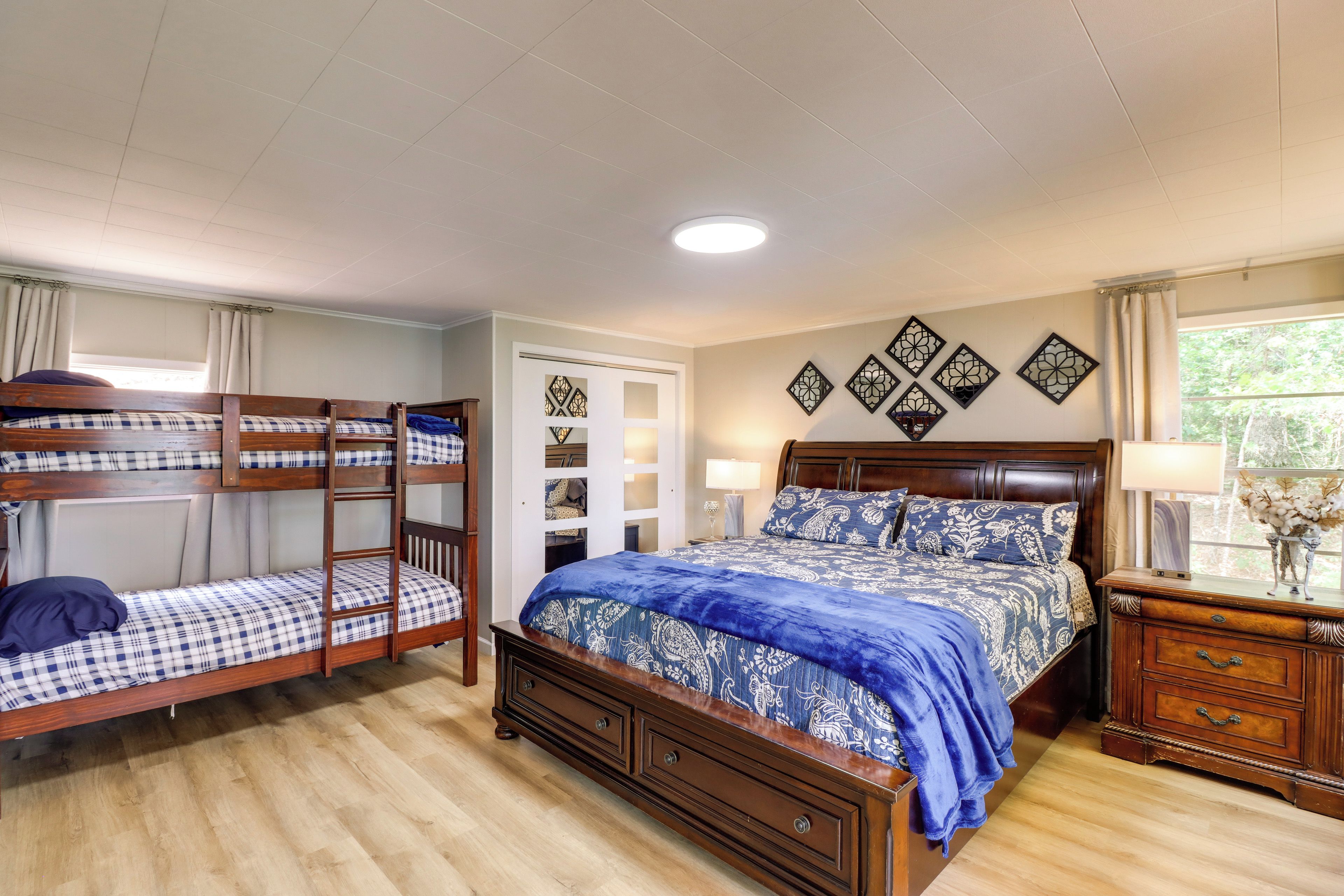Un dormitorio con una cama litera, una cama individual, un aparador y decoración en la pared.