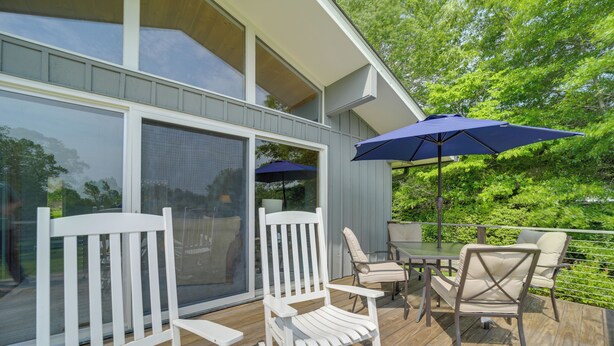 A deck with outdoor furniture, including white rocking chairs and a table, and a large blue umbrella. - Centrally Located Brevard Home w/ Deck & Fire Pit! (Brevard)
