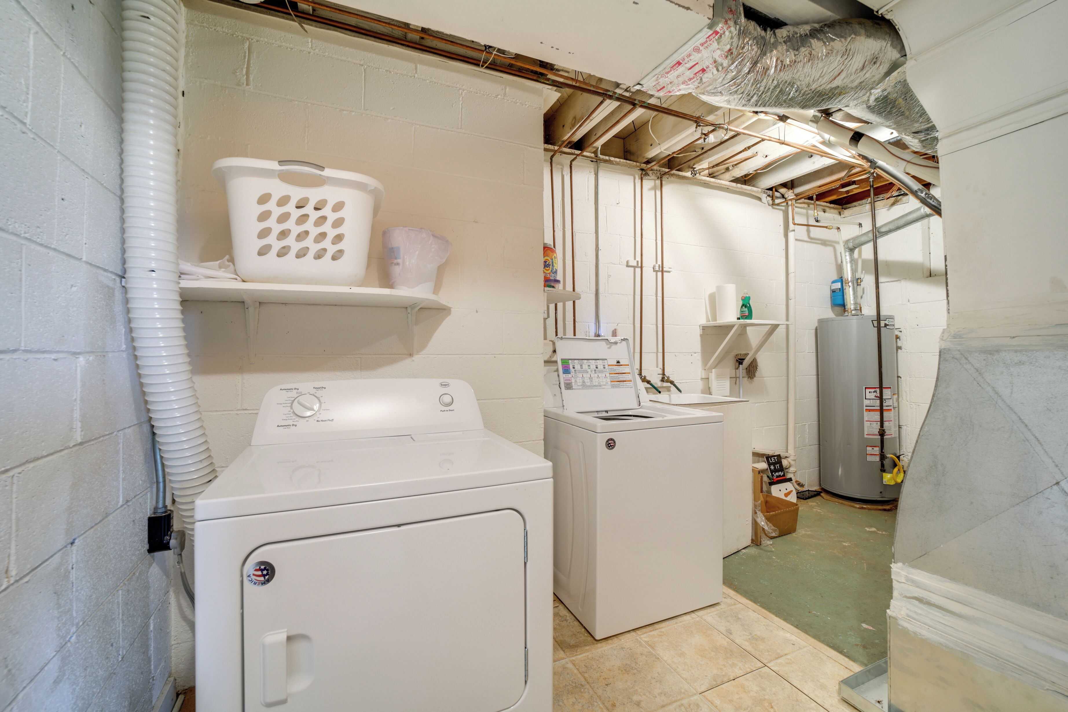 A laundry room with two washing machines, a dryer, and a water heater.