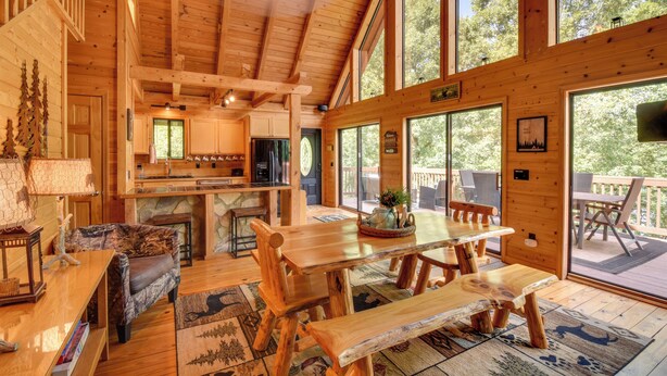 A spacious wooden cabin with a large dining table, a cozy seating area, and a kitchen. - Lakefront Six Mile Vacation Rental w/ Dock (Six Mile)