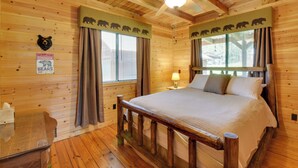 A wooden cabin bedroom with a bed, a nightstand, a lamp, and a ceiling fan. - Lakefront Six Mile Vacation Rental w/ Dock (Six Mile)
