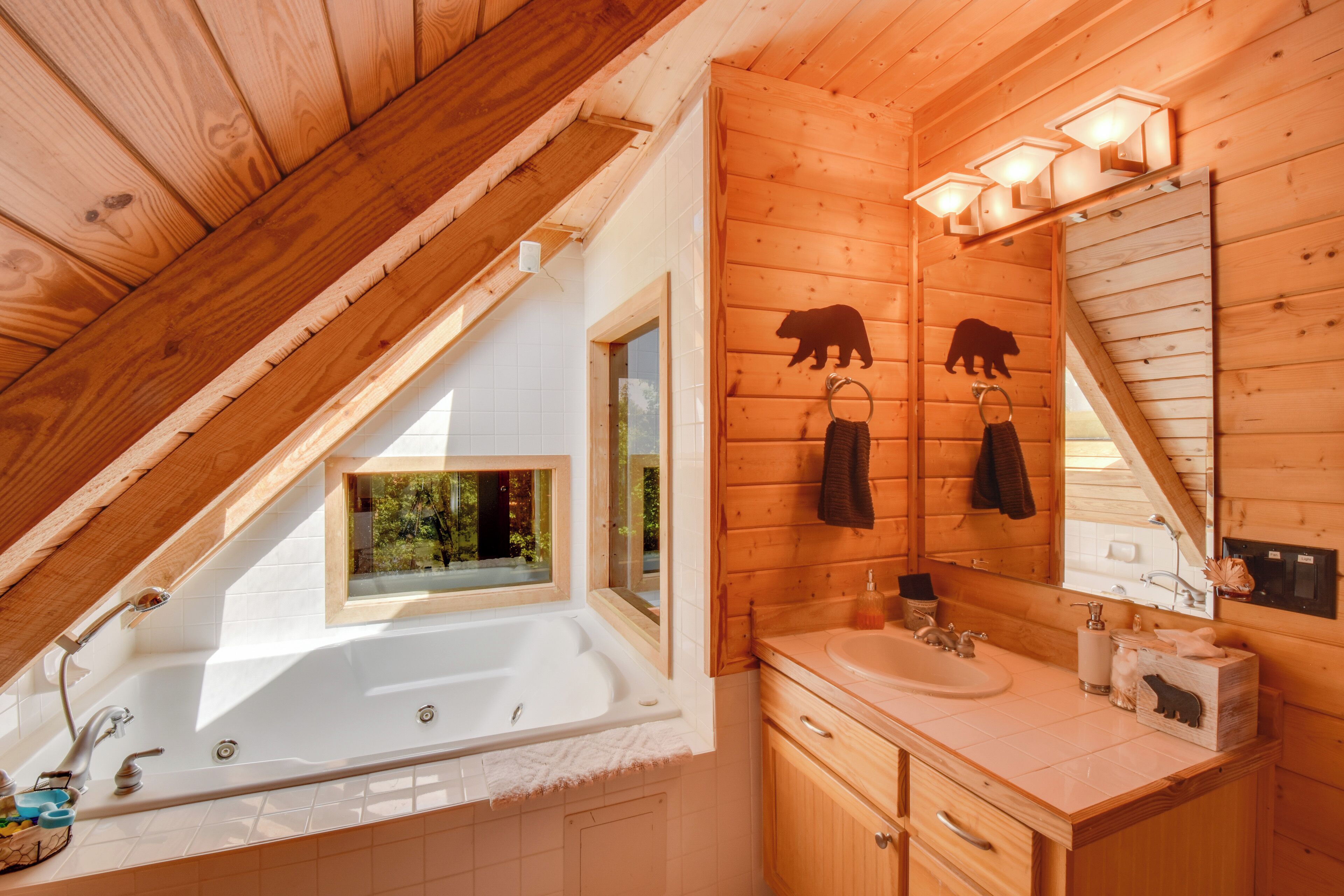 A wooden cabin bathroom with a bathtub, sink, and wooden cabinets.