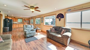 A spacious living area with a large window, a ceiling fan, and a view of the outdoors. - Deck & Water View: Cozy Kentucky Lake Getaway (New Concord)