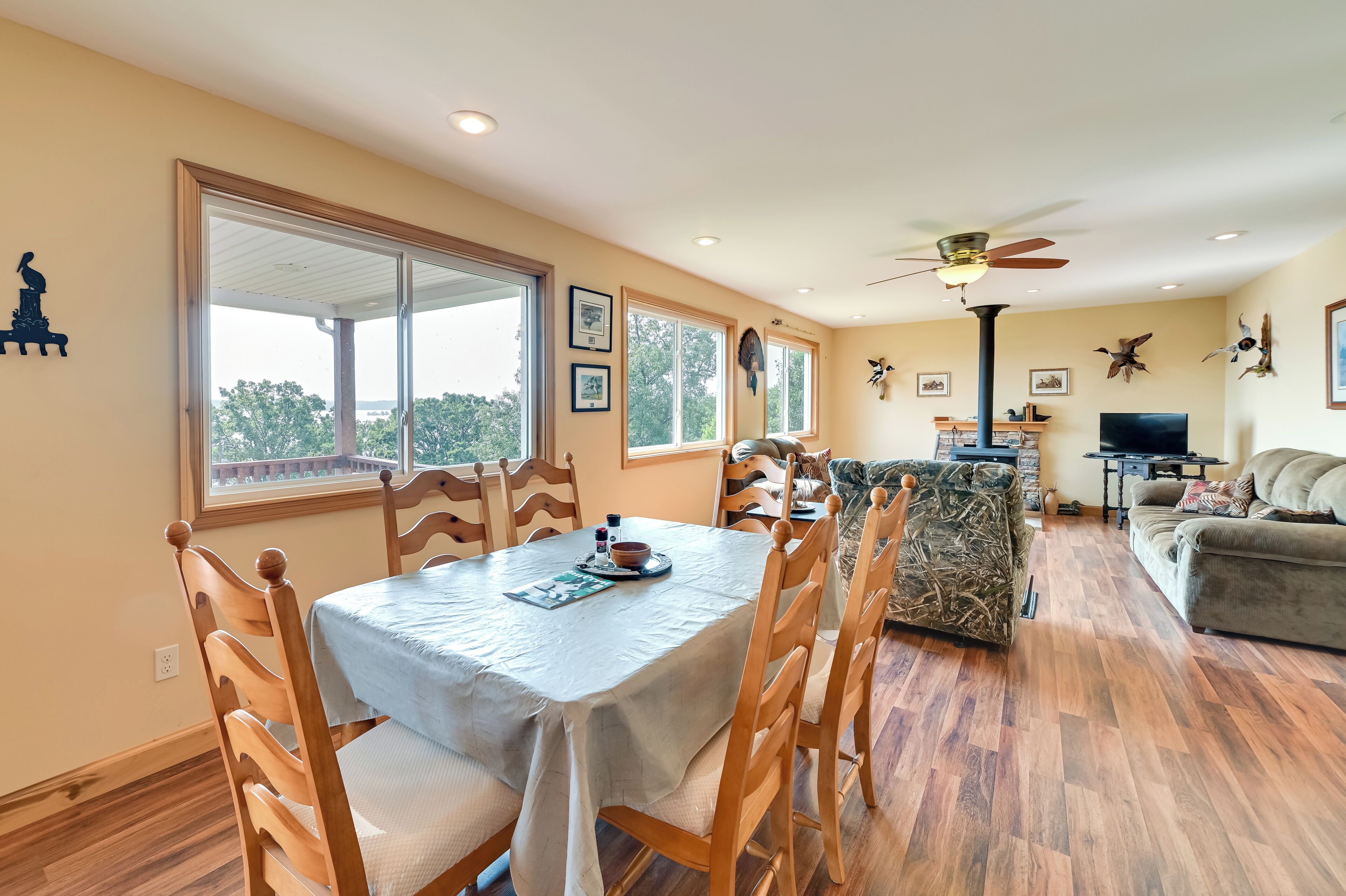 A dining area with a table set for four, wooden chairs, and a view through large windows.