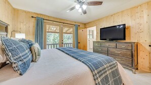Een slaapkamer met een bed, plafondventilator, televisie en een dressoir.