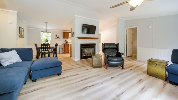A living room with a fireplace, blue sofas, a leather chair, and a ceiling fan. - North Carolina Home Near Mountain Biking & Fishing (Pisgah Forest)