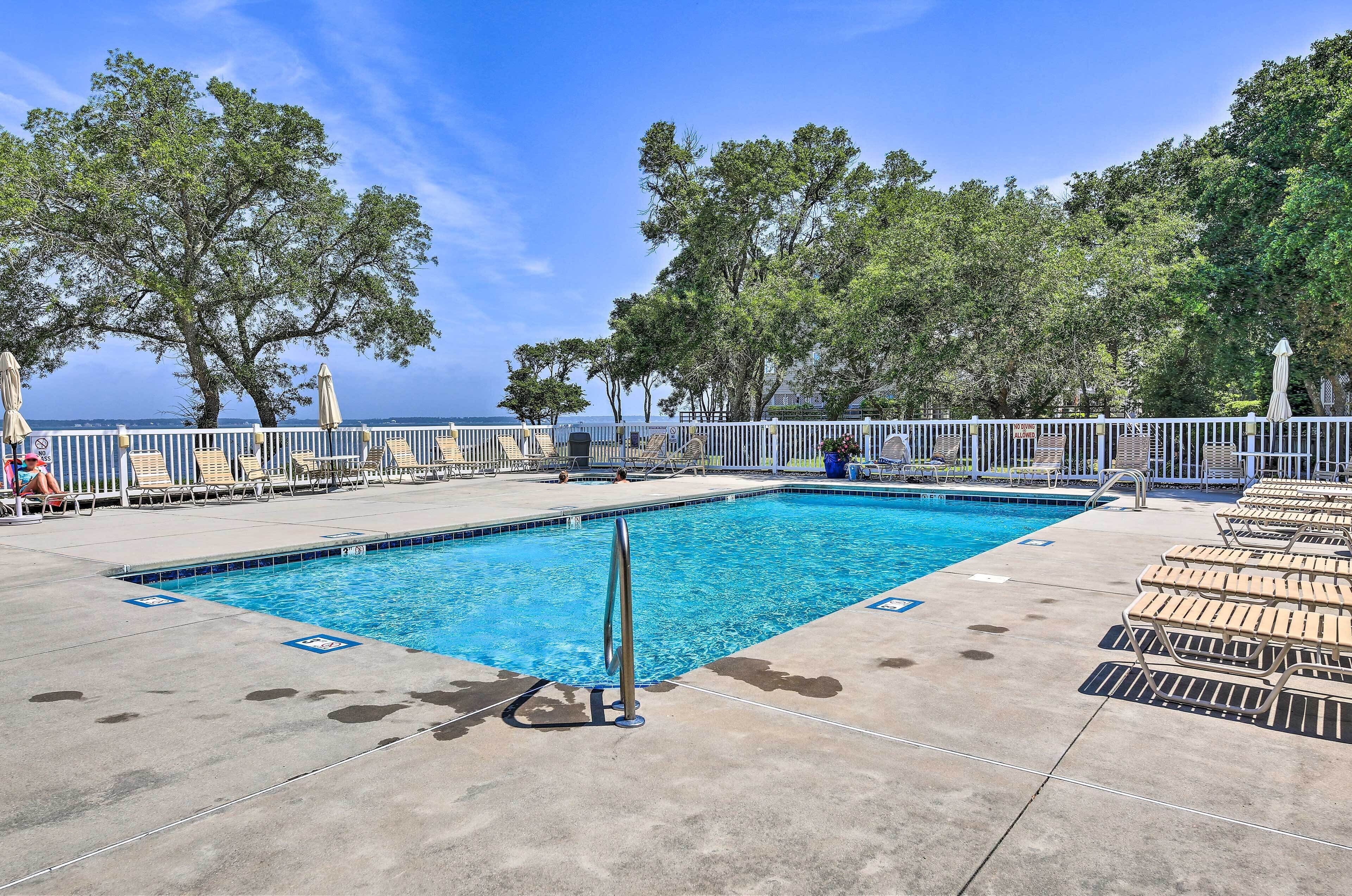 A pool area with lounge chairs and a view of the sea.