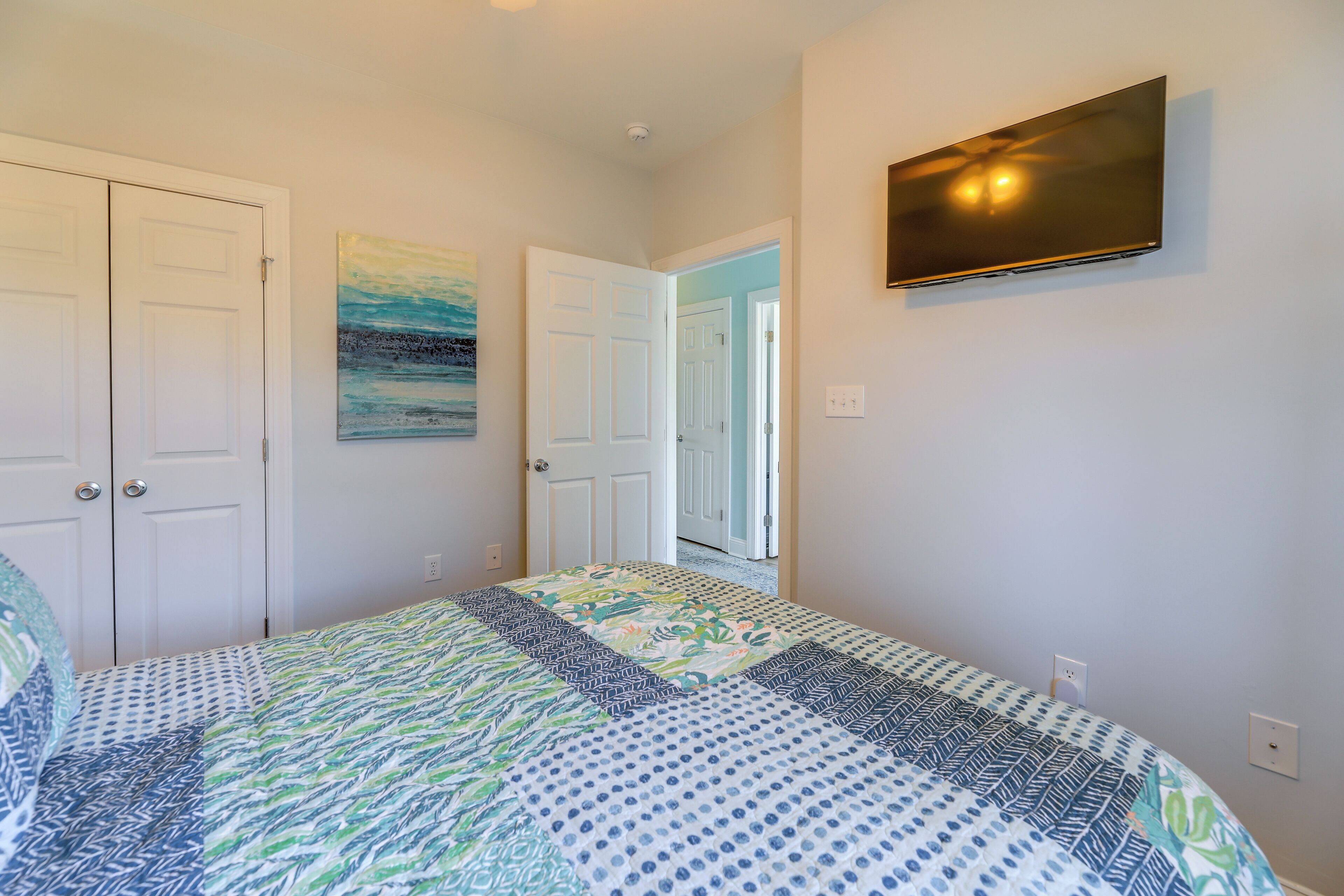 A bedroom with a bed, a TV, and two doors.
