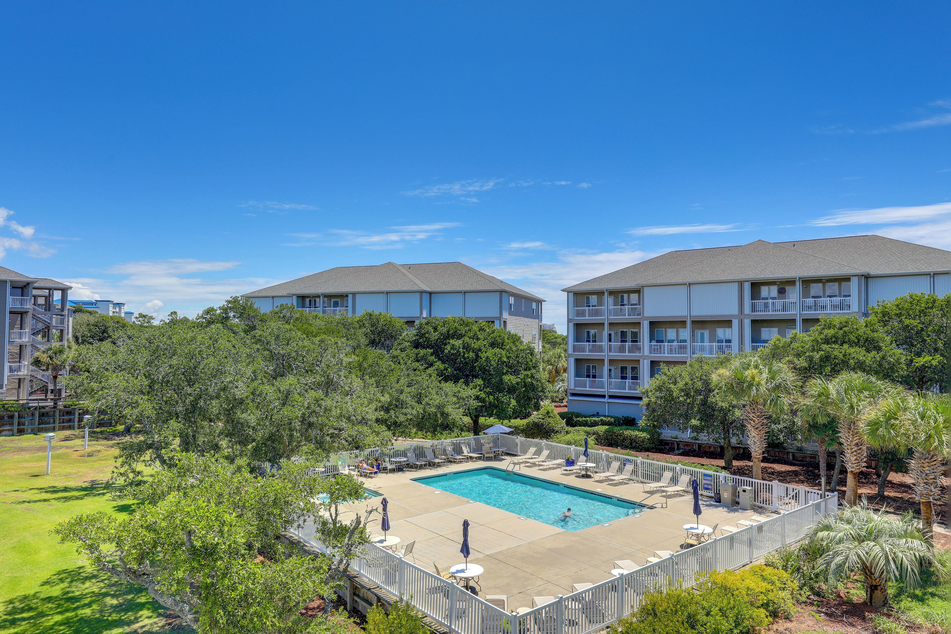 A swimming pool surrounded by a fence, with multiple buildings in the background.
