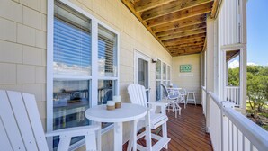 A covered outdoor area with white chairs and tables, wooden ceiling beams, and a view of the landscape. - Ocean Club Condo: Spectacular View & Beach Access! (Atlantic Beach)