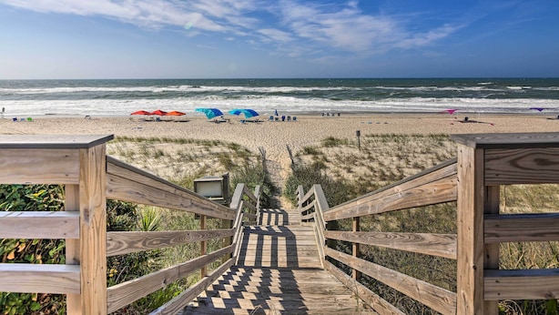 A wooden staircase leading to a beach with umbrellas and chairs. - Ocean Club Condo: Spectacular View & Beach Access! (Atlantic Beach)
