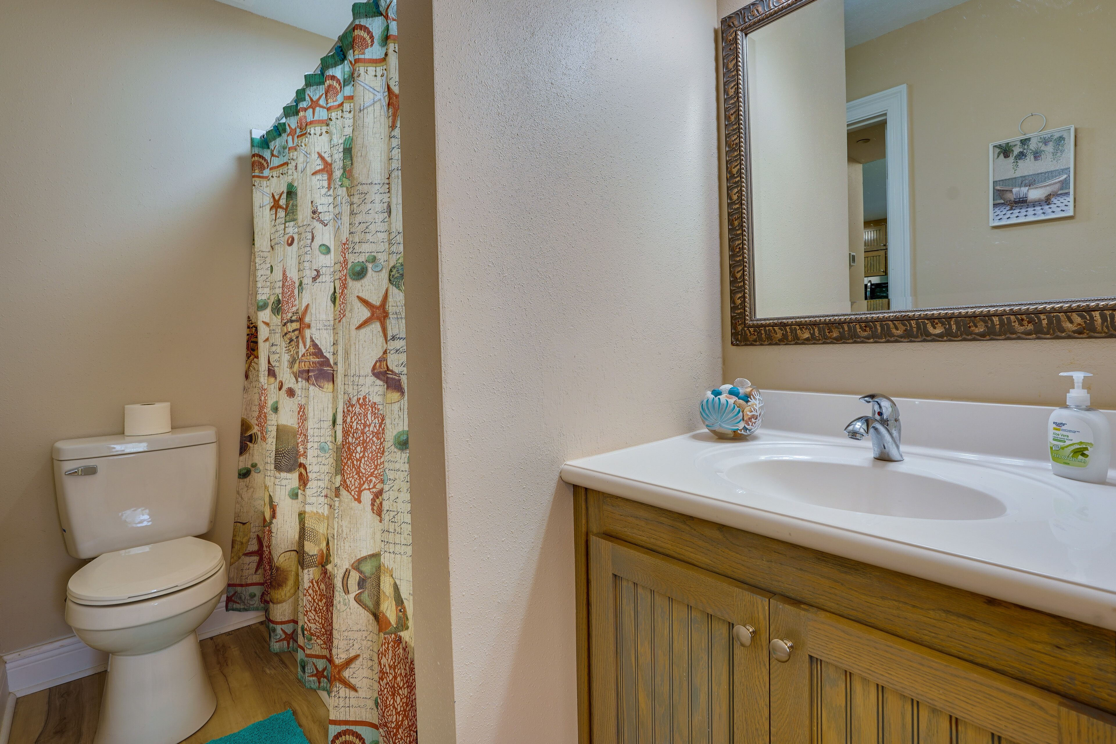 A bathroom with a toilet, sink, mirror, and patterned shower curtain.