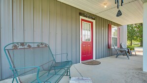A metal bench and a red door on a porch with a metal fence backdrop. - Kentucky Retreat Near Williamstown Lake! (Williamstown)