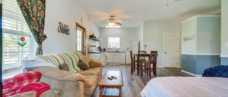 A cozy living room with a sofa, a coffee table, and a dining area with chairs and a table.