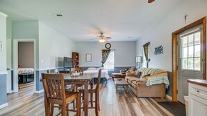 A spacious living room with a dining area, a ceiling fan, and a large window. - Kentucky Retreat Near Williamstown Lake! (Williamstown)