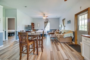 Amplia sala de estar con mesa de comedor, sillas de madera, sofá y ventilador de techo.