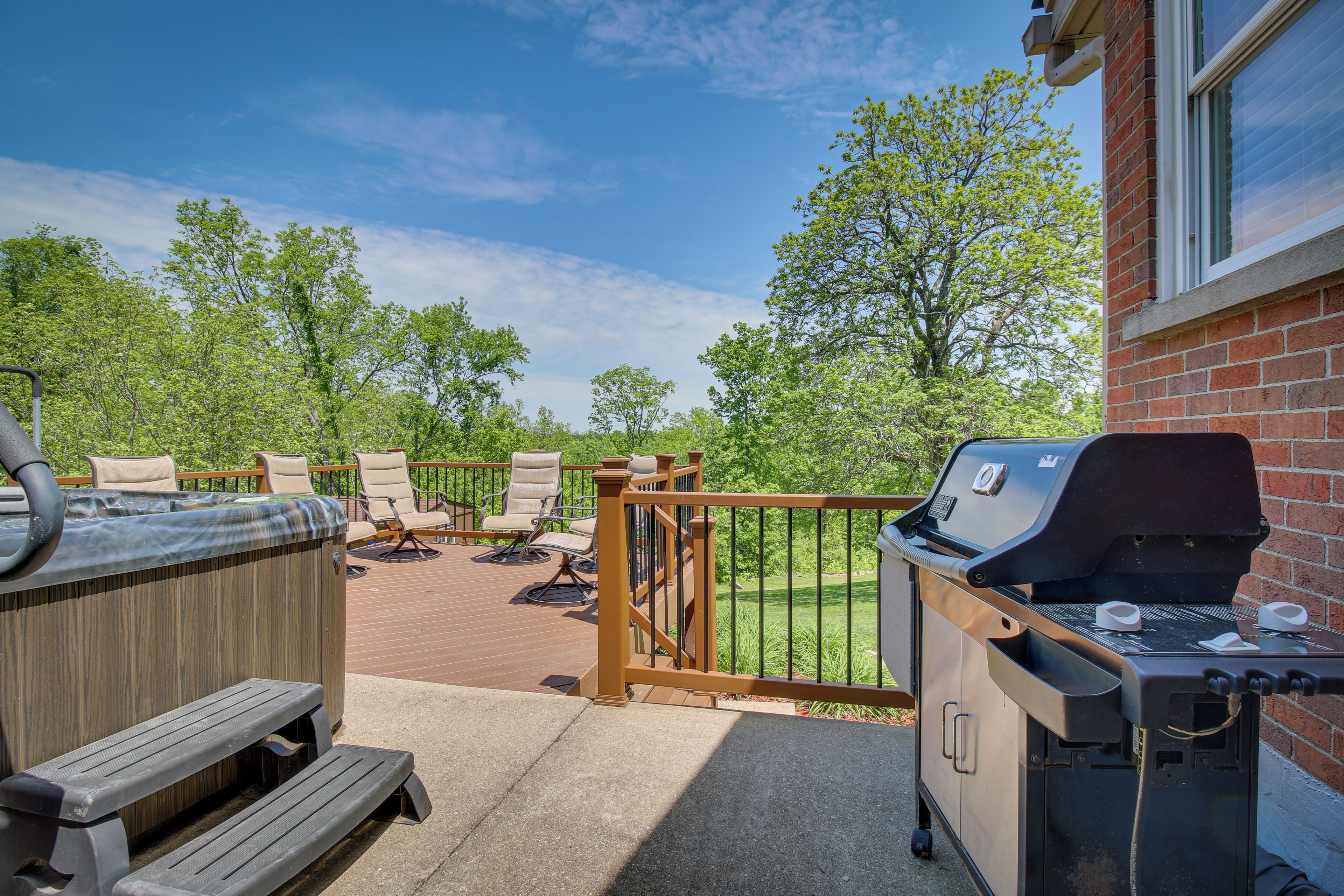 A patio with a hot tub, outdoor seating, and a barbecue grill.
