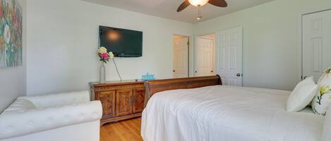A bedroom with a bed, a dresser, a television, and a ceiling fan.