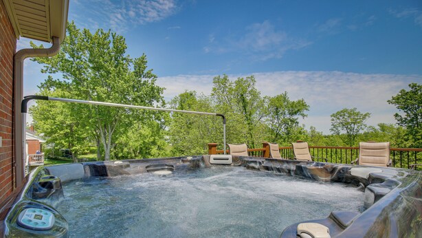 Un bain à remous doté d’une cascade, entouré de meubles de jardin et d’arbres.