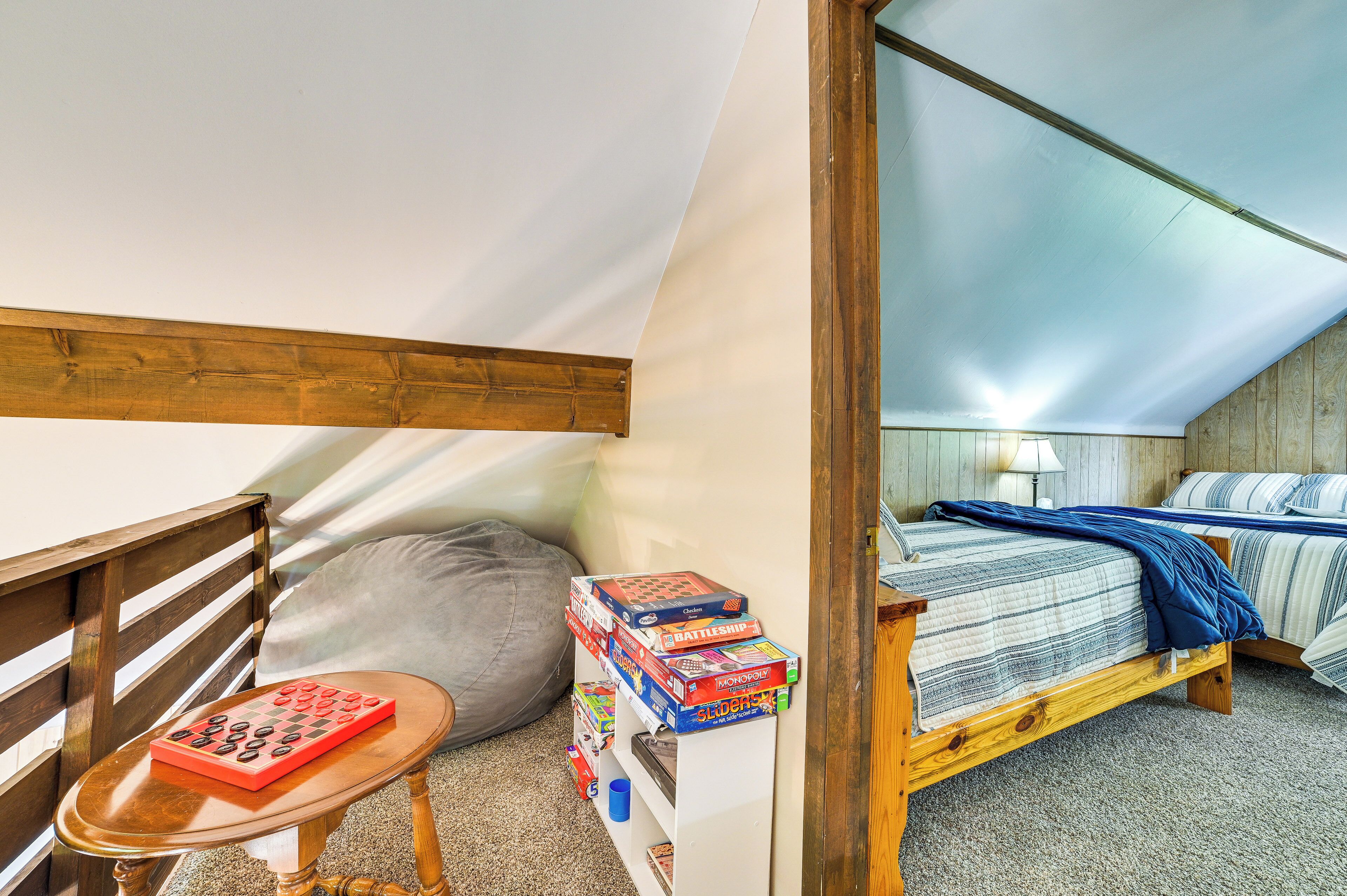A cozy attic bedroom with a sloped ceiling, a wooden bench, and a collection of board games.